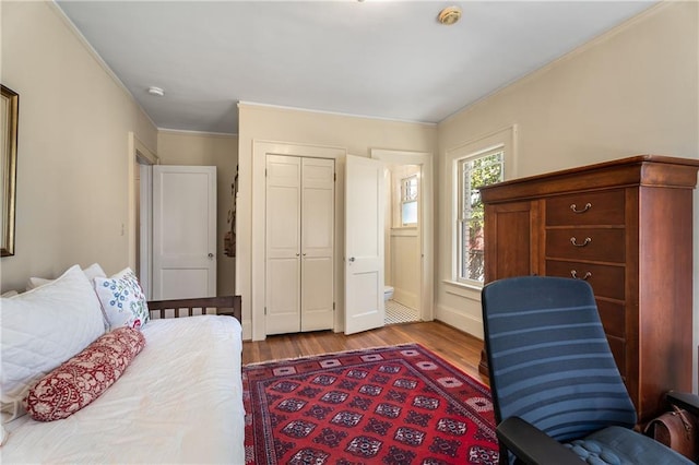 bedroom with a closet, crown molding, and wood finished floors