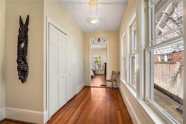 hallway with dark wood finished floors and baseboards