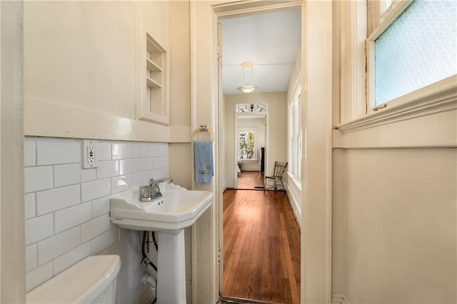 bathroom with toilet, a sink, tile walls, and wood finished floors