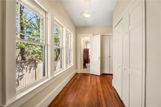 corridor featuring plenty of natural light, dark wood finished floors, and baseboards