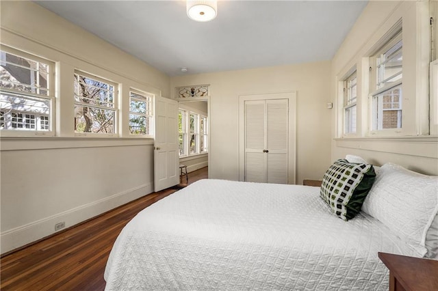 bedroom with a closet, baseboards, and dark wood-type flooring