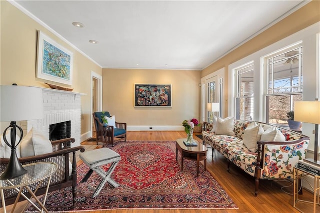 living area with a fireplace, baseboards, crown molding, and wood finished floors