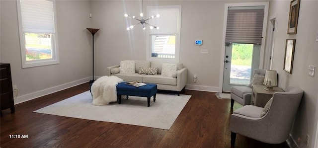 living room with dark wood-type flooring, a chandelier, and a healthy amount of sunlight