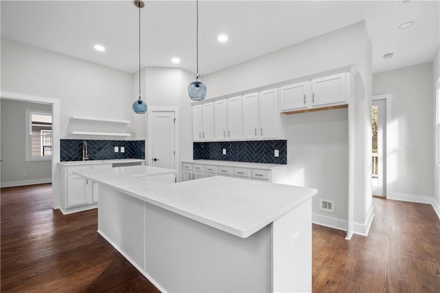 kitchen featuring decorative light fixtures, white cabinets, dark hardwood / wood-style floors, and a kitchen island