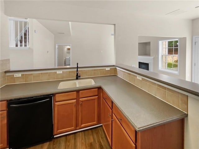 kitchen with dark hardwood / wood-style floors, black dishwasher, sink, and backsplash