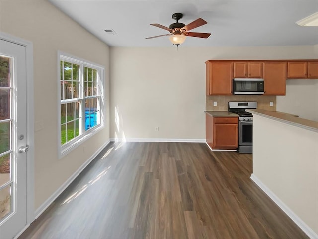 kitchen featuring tasteful backsplash, ceiling fan, appliances with stainless steel finishes, and dark wood-type flooring