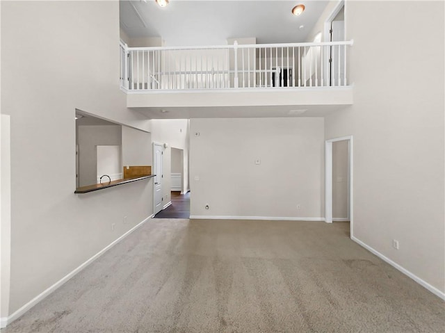 unfurnished living room with carpet and a towering ceiling