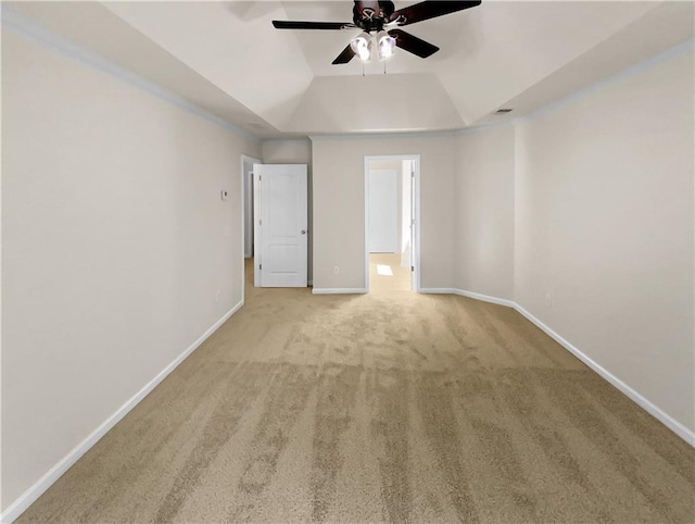 spare room with a tray ceiling, light colored carpet, and ceiling fan