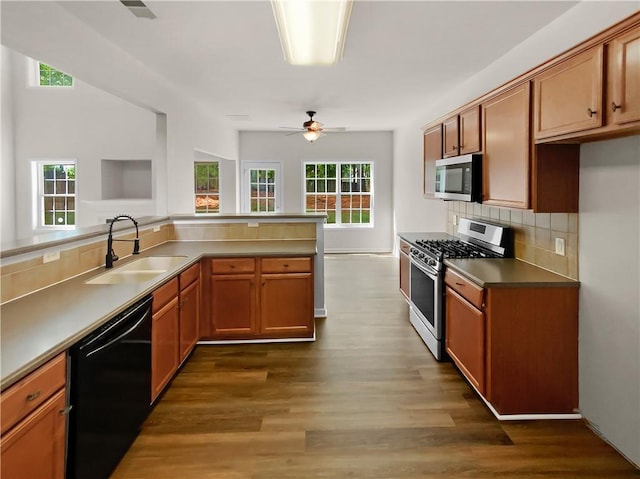 kitchen featuring dark wood-type flooring, sink, ceiling fan, stainless steel appliances, and decorative backsplash