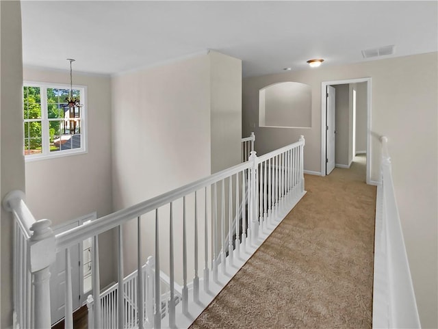 hall featuring carpet flooring and a notable chandelier