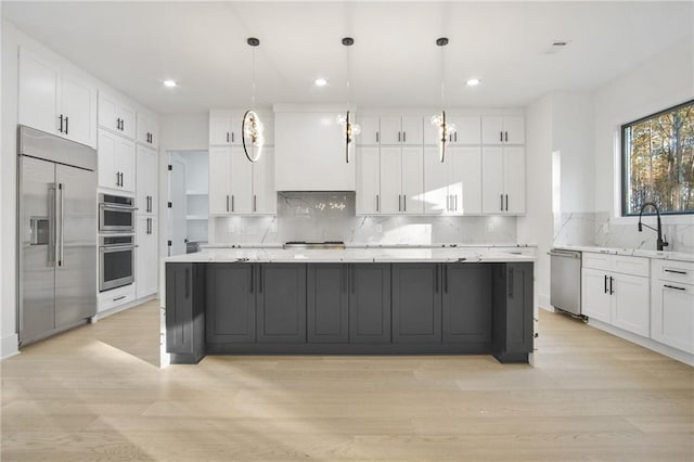 kitchen featuring stainless steel appliances, pendant lighting, and white cabinets