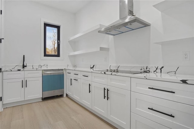 kitchen featuring stainless steel dishwasher, island exhaust hood, white cabinetry, light hardwood / wood-style flooring, and light stone countertops