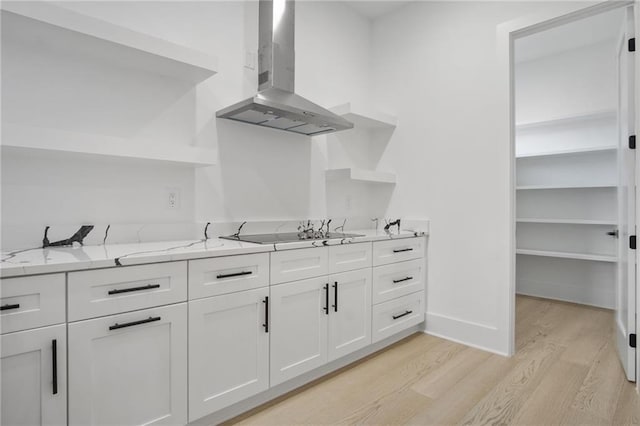 kitchen with white cabinetry, light hardwood / wood-style floors, ventilation hood, electric cooktop, and light stone counters