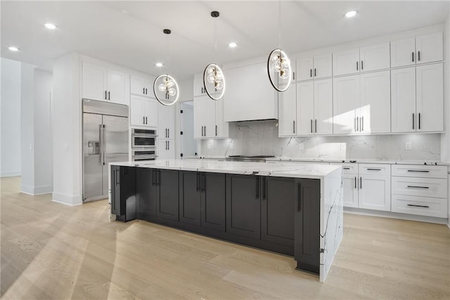 kitchen with light wood-type flooring, stainless steel appliances, white cabinets, and a spacious island