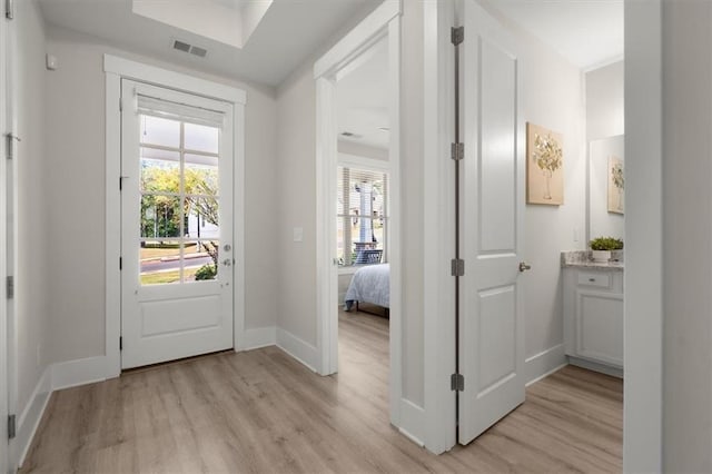 doorway to outside featuring light wood-style flooring, visible vents, and baseboards