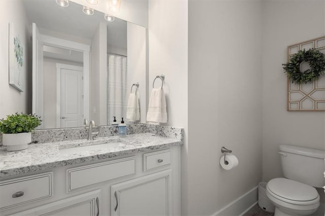 bathroom with toilet, baseboards, and vanity