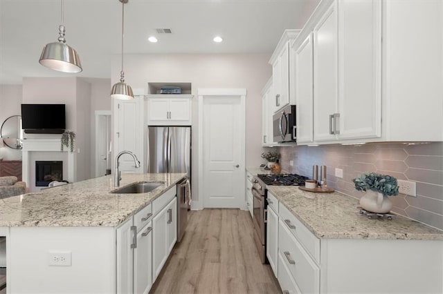 kitchen featuring white cabinetry, sink, hanging light fixtures, a kitchen island with sink, and stainless steel appliances