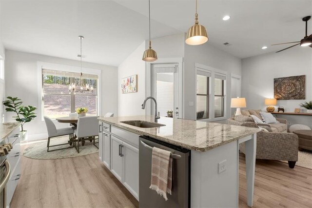 kitchen featuring appliances with stainless steel finishes, decorative light fixtures, sink, white cabinets, and a center island with sink