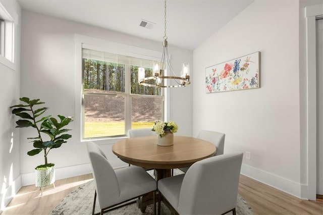 dining space featuring baseboards, wood finished floors, visible vents, and a notable chandelier