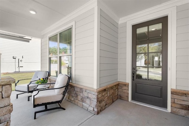 view of exterior entry featuring stone siding and a porch