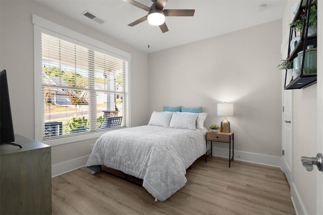 bedroom featuring light wood-style flooring, visible vents, baseboards, and ceiling fan