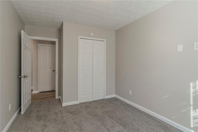 unfurnished bedroom with light carpet, a closet, and a textured ceiling