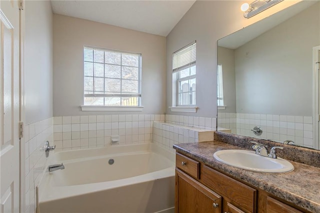 bathroom with vanity, vaulted ceiling, and a washtub