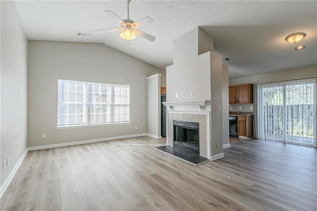 unfurnished living room featuring ceiling fan, lofted ceiling, light hardwood / wood-style floors, and a tile fireplace