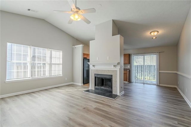 unfurnished living room with a fireplace, vaulted ceiling, ceiling fan, and light wood-type flooring