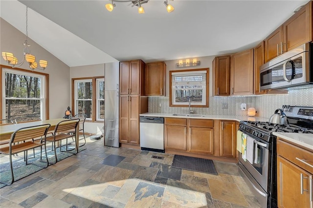 kitchen with stone tile floors, appliances with stainless steel finishes, light countertops, and a sink