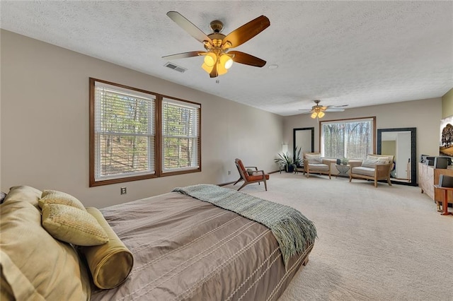 carpeted bedroom with a textured ceiling, ceiling fan, and visible vents