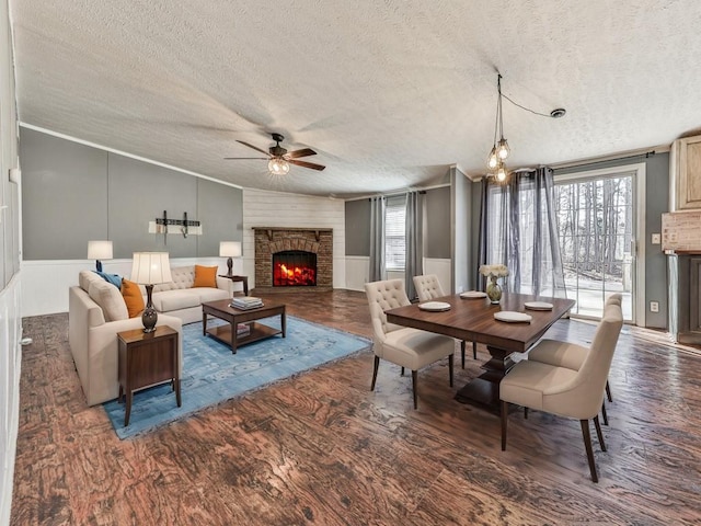 interior space with wood finished floors, a ceiling fan, a fireplace, vaulted ceiling, and a textured ceiling