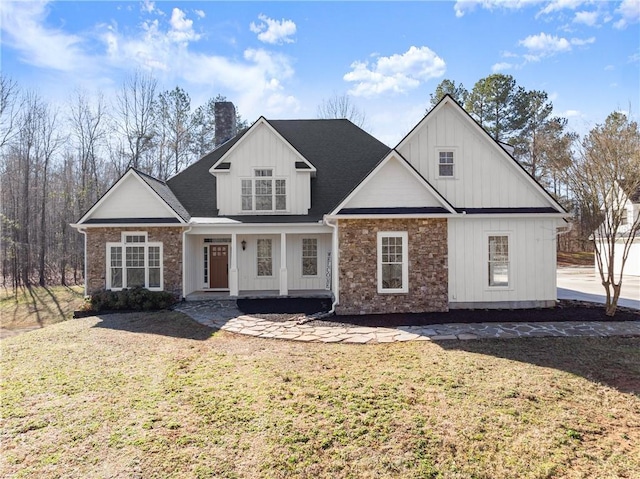 view of front of house featuring stone siding, a front yard, board and batten siding, and a chimney