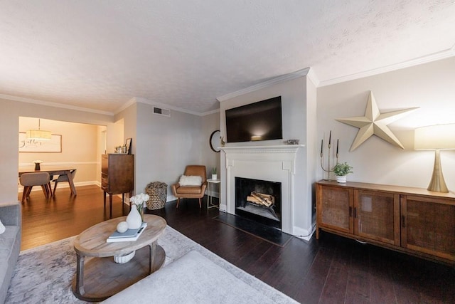 living room featuring crown molding, dark wood-type flooring, and a textured ceiling