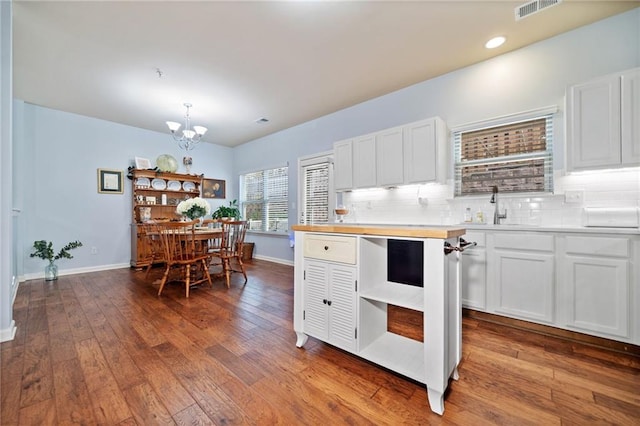 kitchen featuring decorative backsplash, white cabinets, a sink, and decorative light fixtures