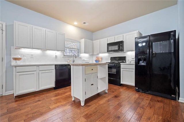 kitchen with black appliances, light countertops, and white cabinets