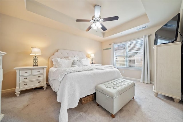 bedroom with baseboards, visible vents, a raised ceiling, and light colored carpet