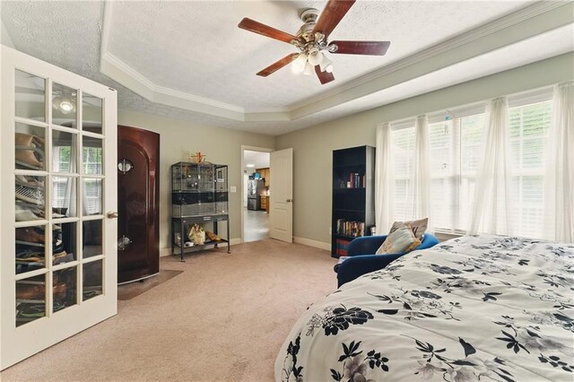 bedroom with a tray ceiling, ornamental molding, carpet, baseboards, and a textured ceiling