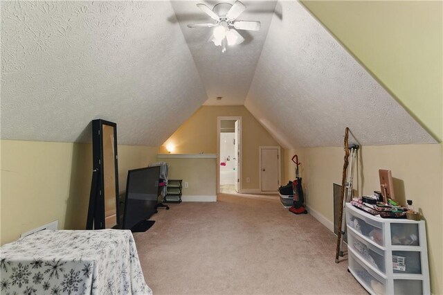 bedroom featuring a textured ceiling, carpet floors, vaulted ceiling, baseboards, and ceiling fan