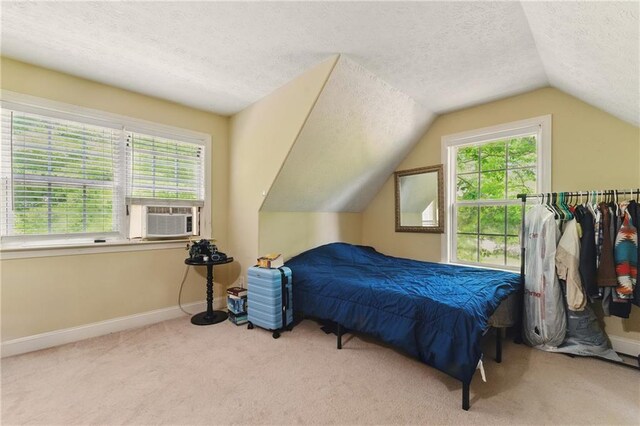 carpeted bedroom with a textured ceiling, cooling unit, vaulted ceiling, and baseboards