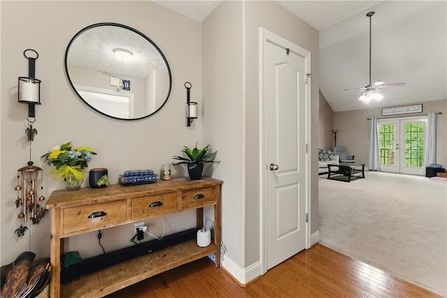 hallway with wood finished floors, baseboards, and vaulted ceiling