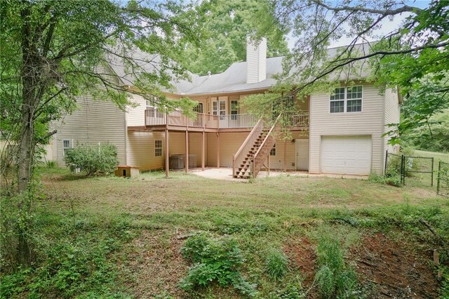 rear view of property featuring stairway, a garage, a chimney, and a deck
