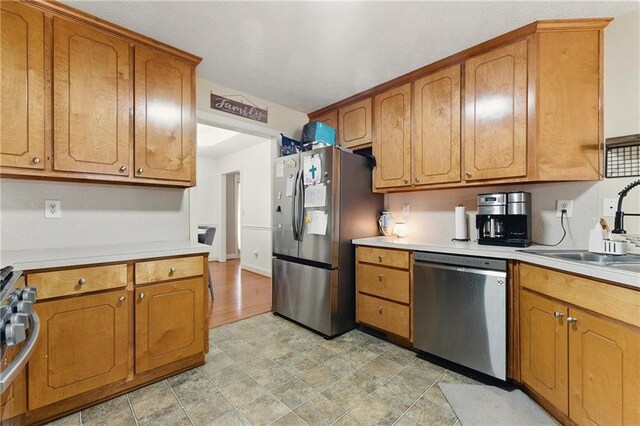 kitchen with stainless steel appliances, brown cabinetry, and a sink