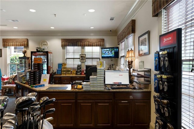 bar with dark stone countertops, crown molding, and dark brown cabinetry