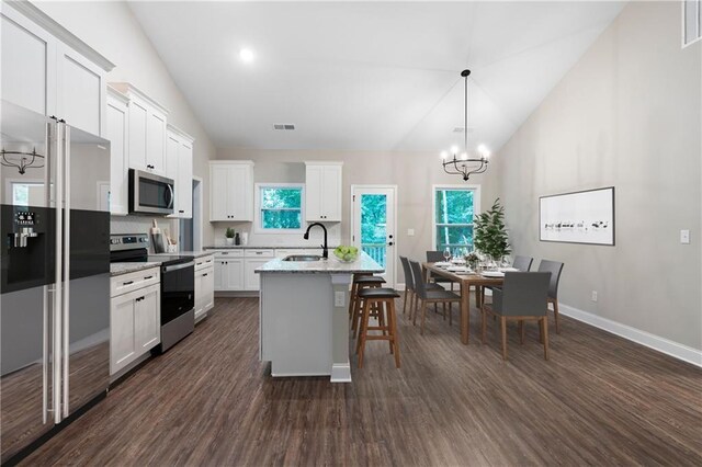 kitchen featuring sink, stainless steel appliances, dark hardwood / wood-style floors, vaulted ceiling, and a center island with sink