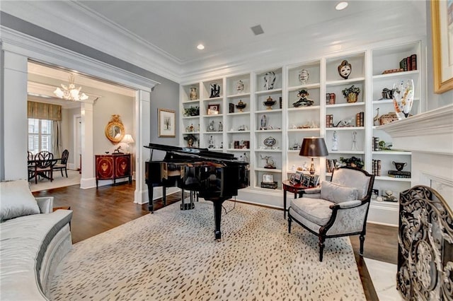 sitting room with a notable chandelier, built in shelves, wood-type flooring, and ornamental molding