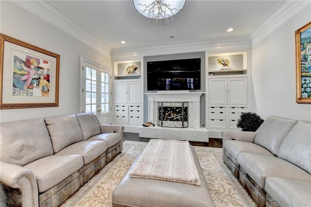 living room featuring built in shelves, french doors, ornamental molding, hardwood / wood-style flooring, and a premium fireplace