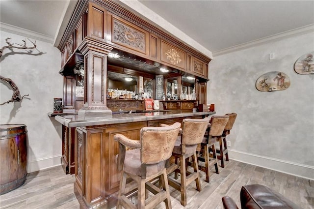 bar with ornamental molding and light hardwood / wood-style flooring