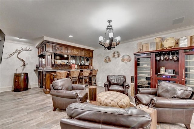 living room with a notable chandelier, crown molding, bar area, and light hardwood / wood-style floors