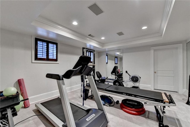 workout room with ornamental molding and a raised ceiling